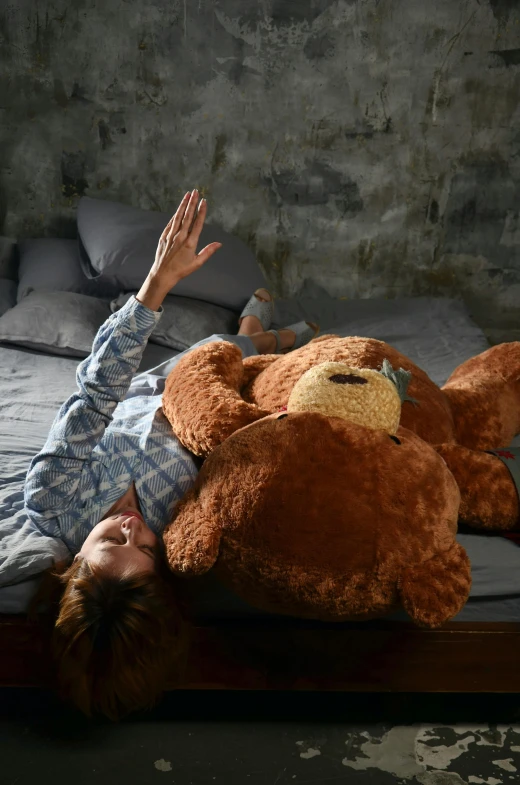 a person laying on top of a brown teddy bear