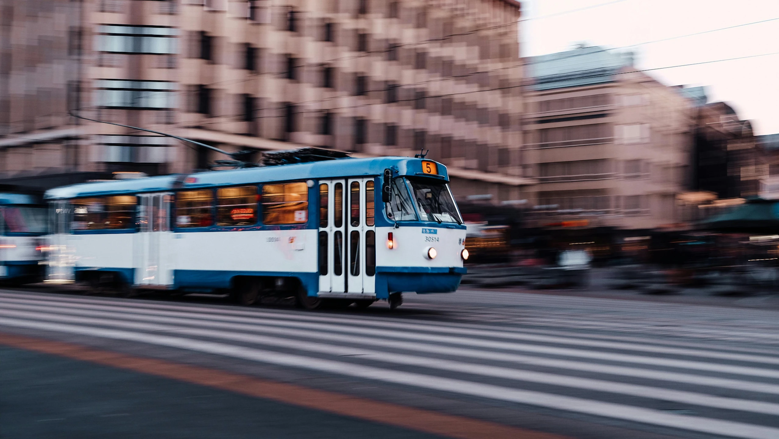 a blue trolly going down a street next to tall buildings