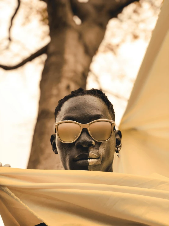 a man is wearing mirrored glasses with his face covered by a blanket