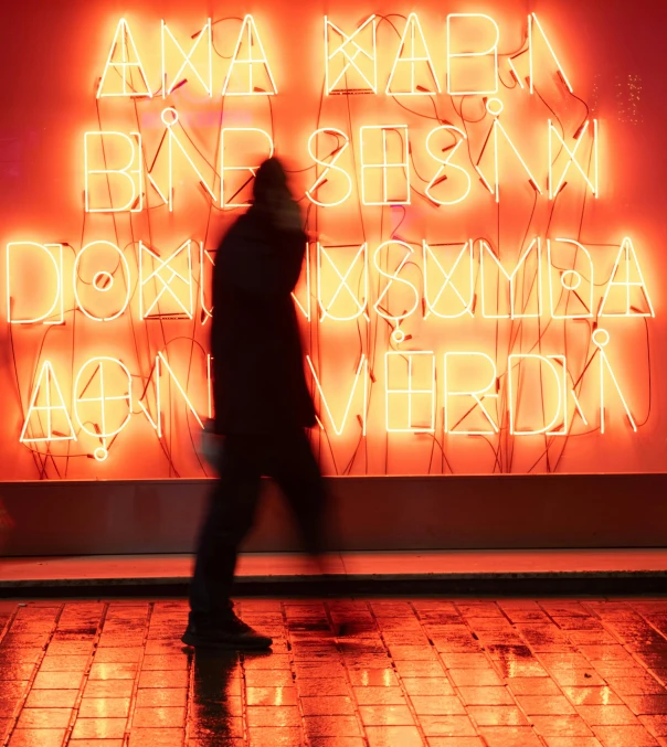 a person walks past an illuminated text panel