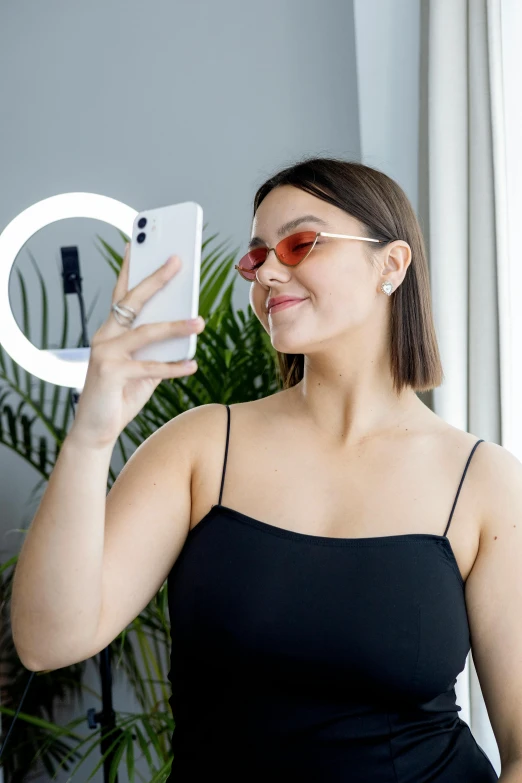 a smiling woman in a black dress is holding a phone