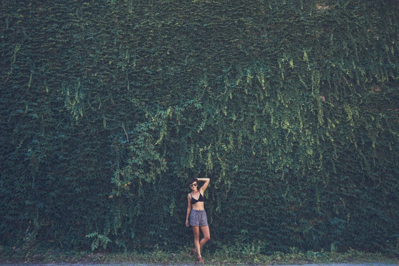 a young woman standing under a huge bush