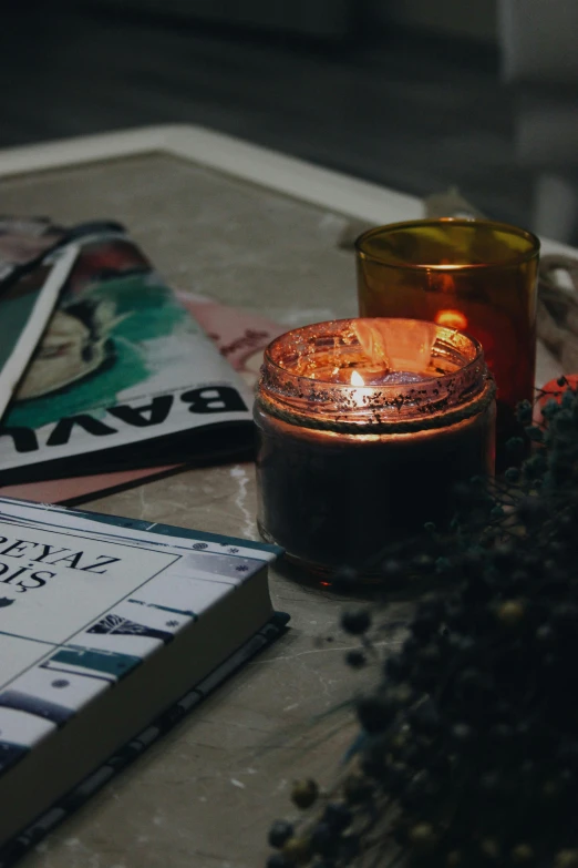 a candle sits on the table next to a book