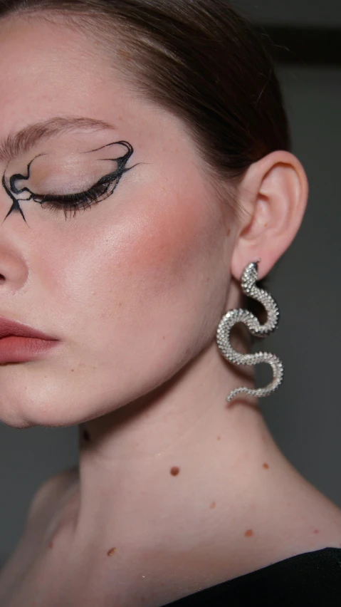 the face is shown with eyeliners and a pair of earrings