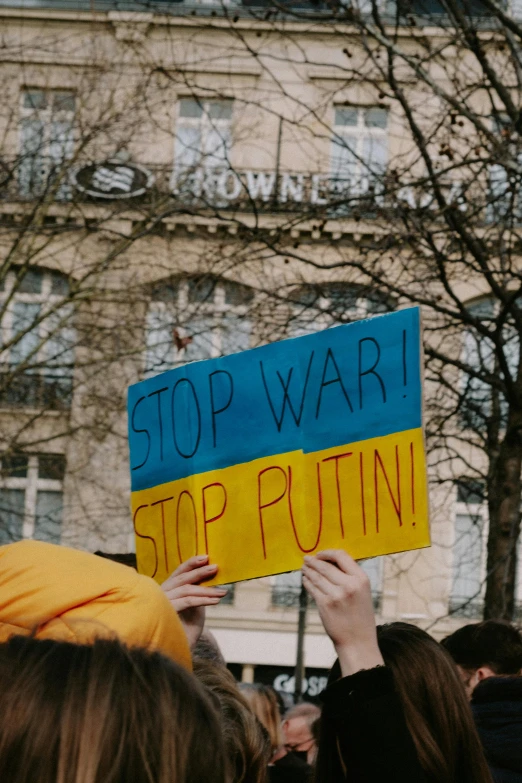 a sign in the middle of a crowd reading stop war