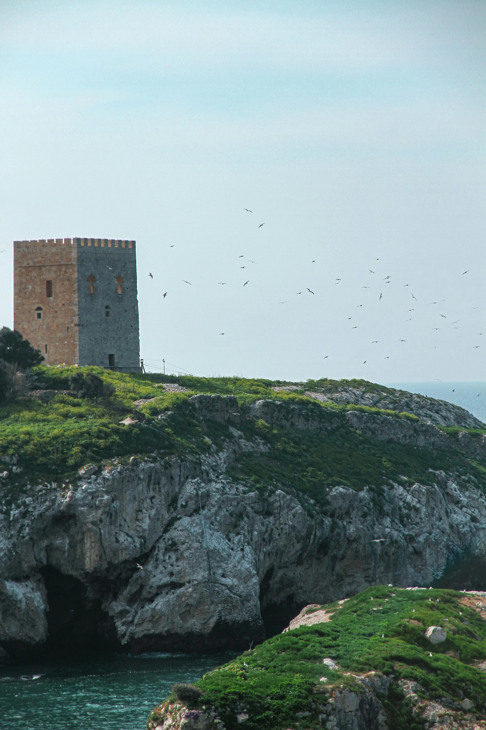 a tower sits on the edge of an island in water