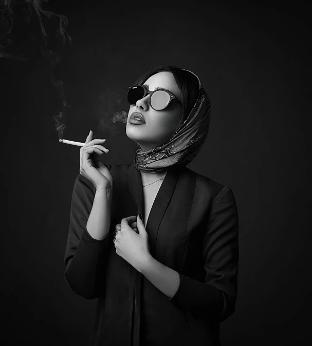 woman in black shirt and scarf holding cigarette with hand on hips