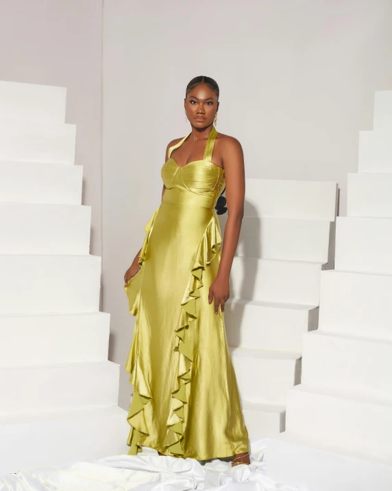 a woman is standing against white blocks wearing a gold dress