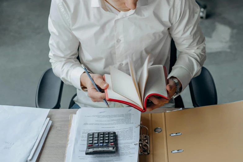 an old man is working with his calculator and book