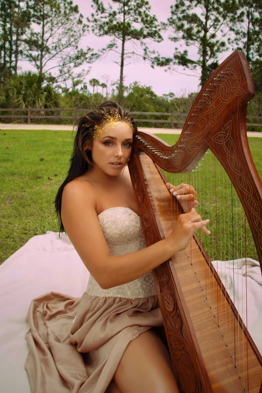 a woman holding onto an instrument sitting on a blanket