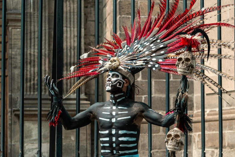 a person with painted face paint holding a rifle in front of a metal gate