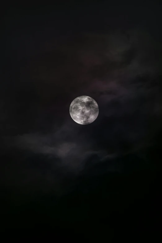 a full moon is seen between the clouds