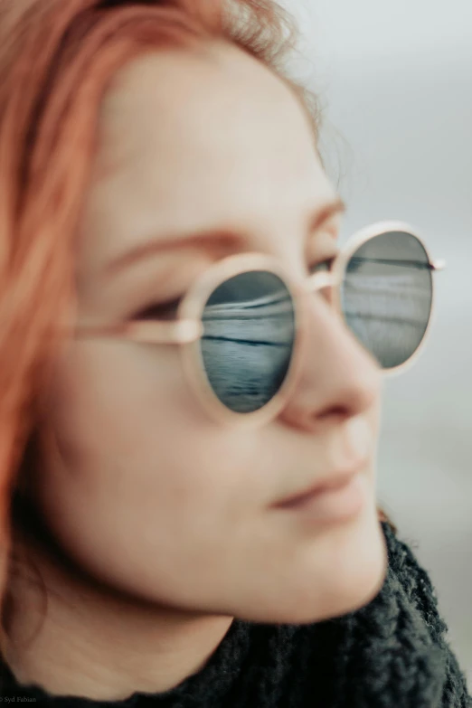 the woman is wearing round sunglasses and smiling