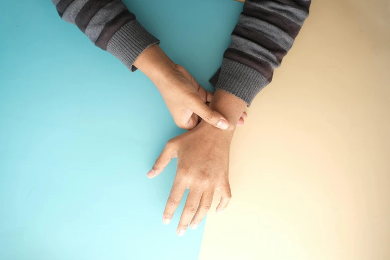 two hands are gripping each other while standing on a blue surface