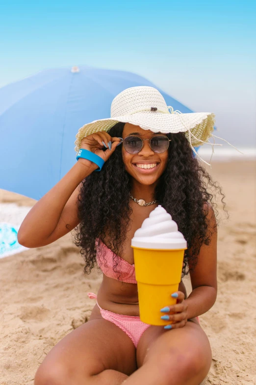 a pretty young lady in a bikini and hat holding a drink