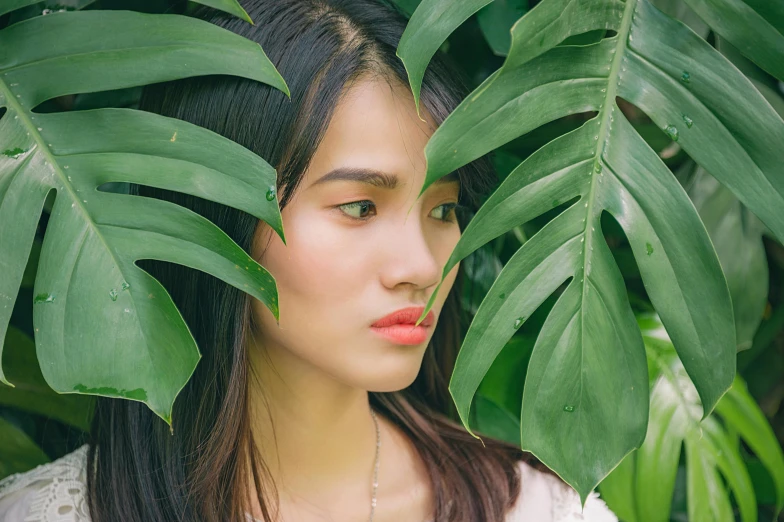 a woman is posing amongst a tree with long, black hair