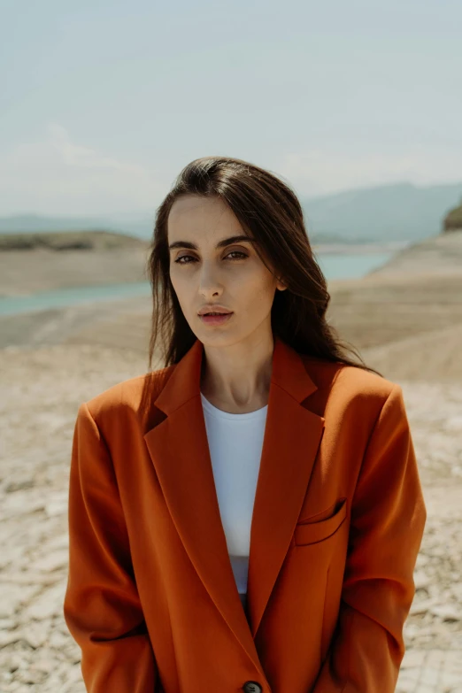 the beautiful woman is posing in an orange jacket