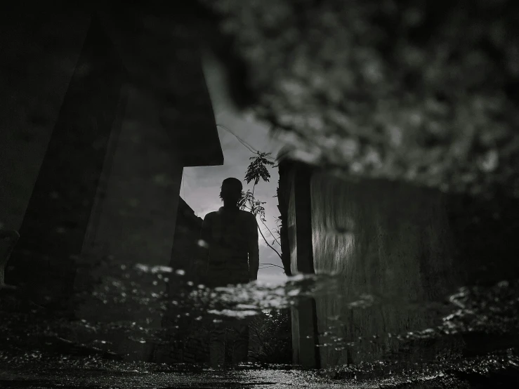 a black and white image shows someone standing in an alley way