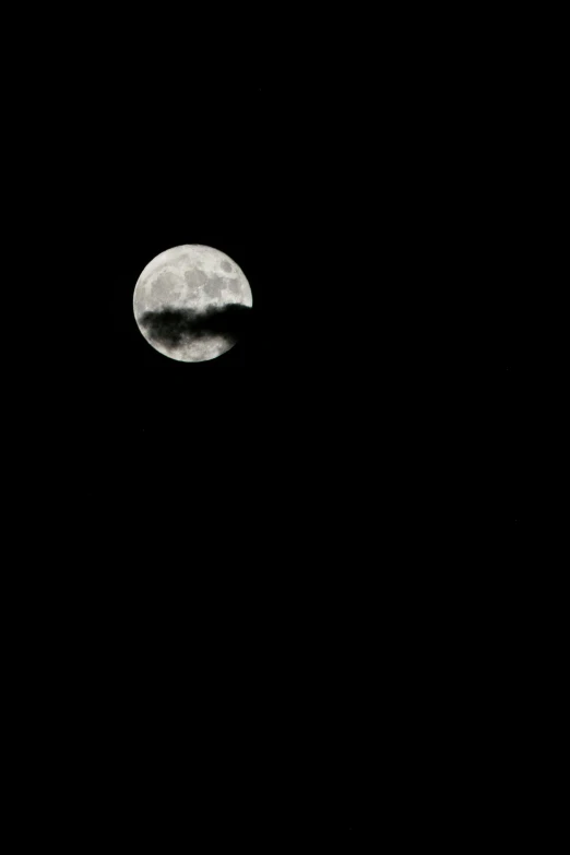 a large full moon rising over a hill top