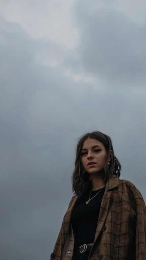 a woman is standing in front of clouds