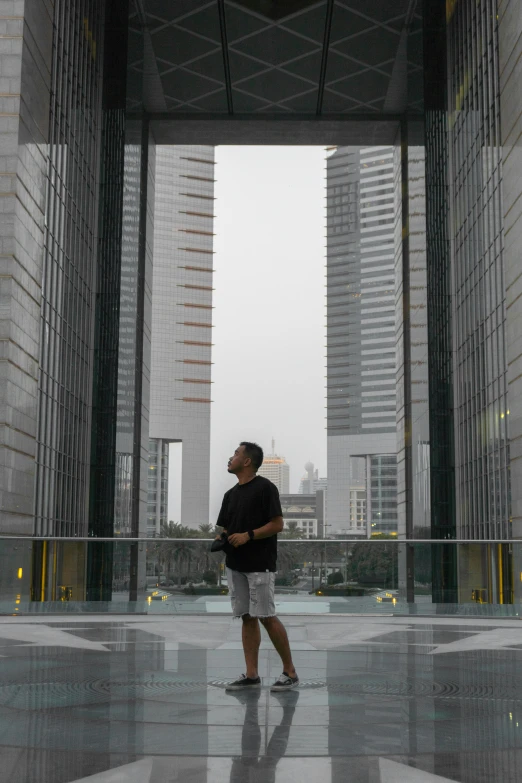 a person walking in an open courtyard with tall buildings