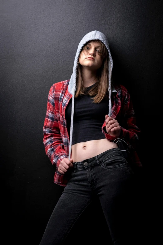 a woman leaning against a wall wearing black pants