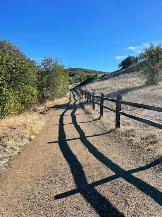 the shadow of a metal fence in front of a field