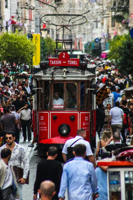 a large group of people walking around and in front of a trolley