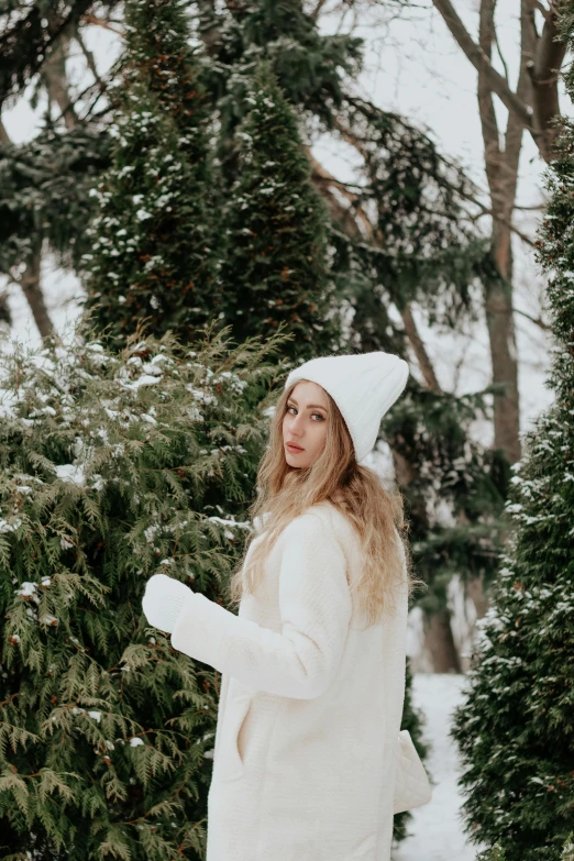 a woman standing in front of snow covered trees