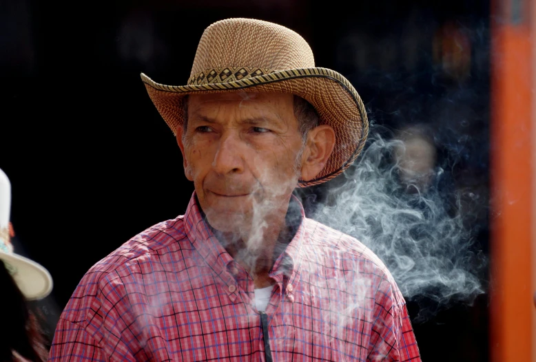 man wearing a cowboy hat smoking soing