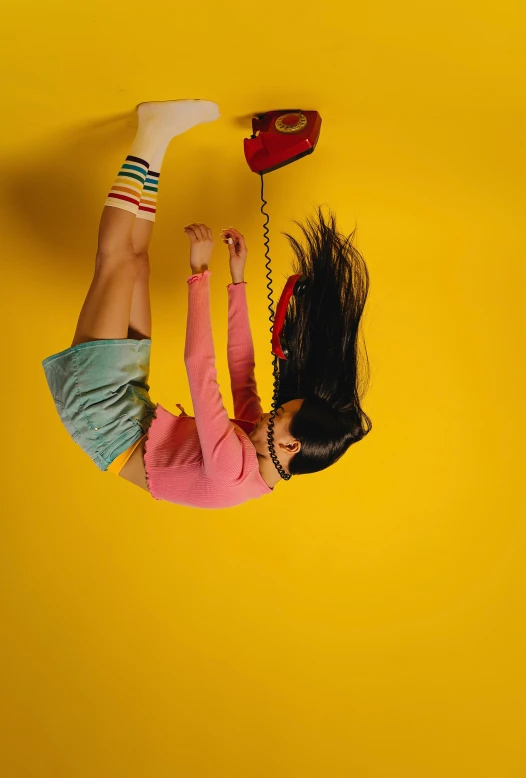 a woman lying on the floor holding an old telephone