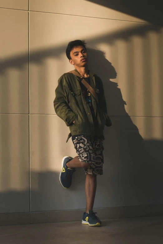 the young man is standing near the wall with his shoes on