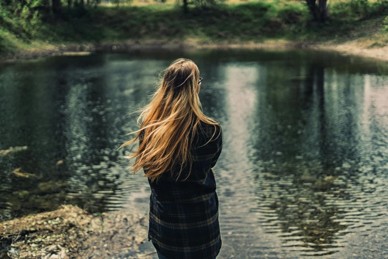 a young woman standing near a pond in the rain