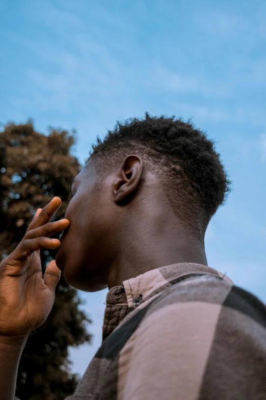 a black man in plaid shirt holding his hand to his mouth