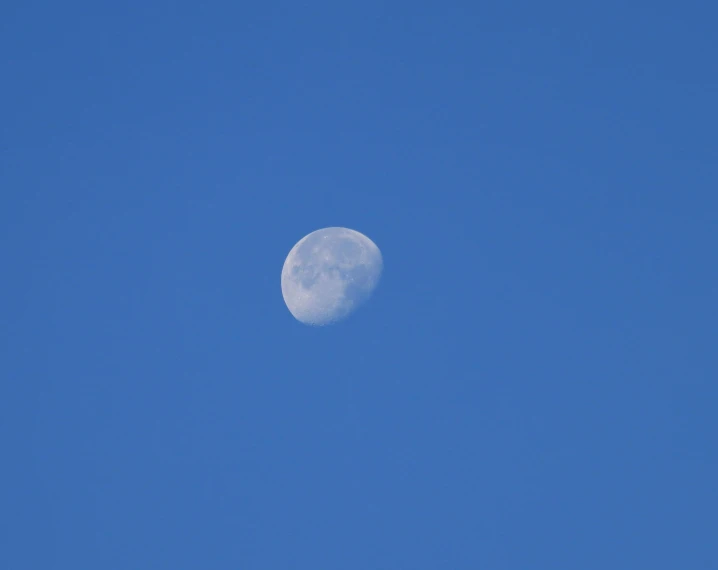 a big moon that is partially visible on a clear day