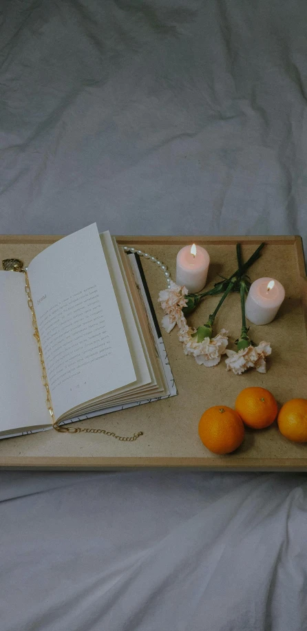 there is an open book next to oranges and candles