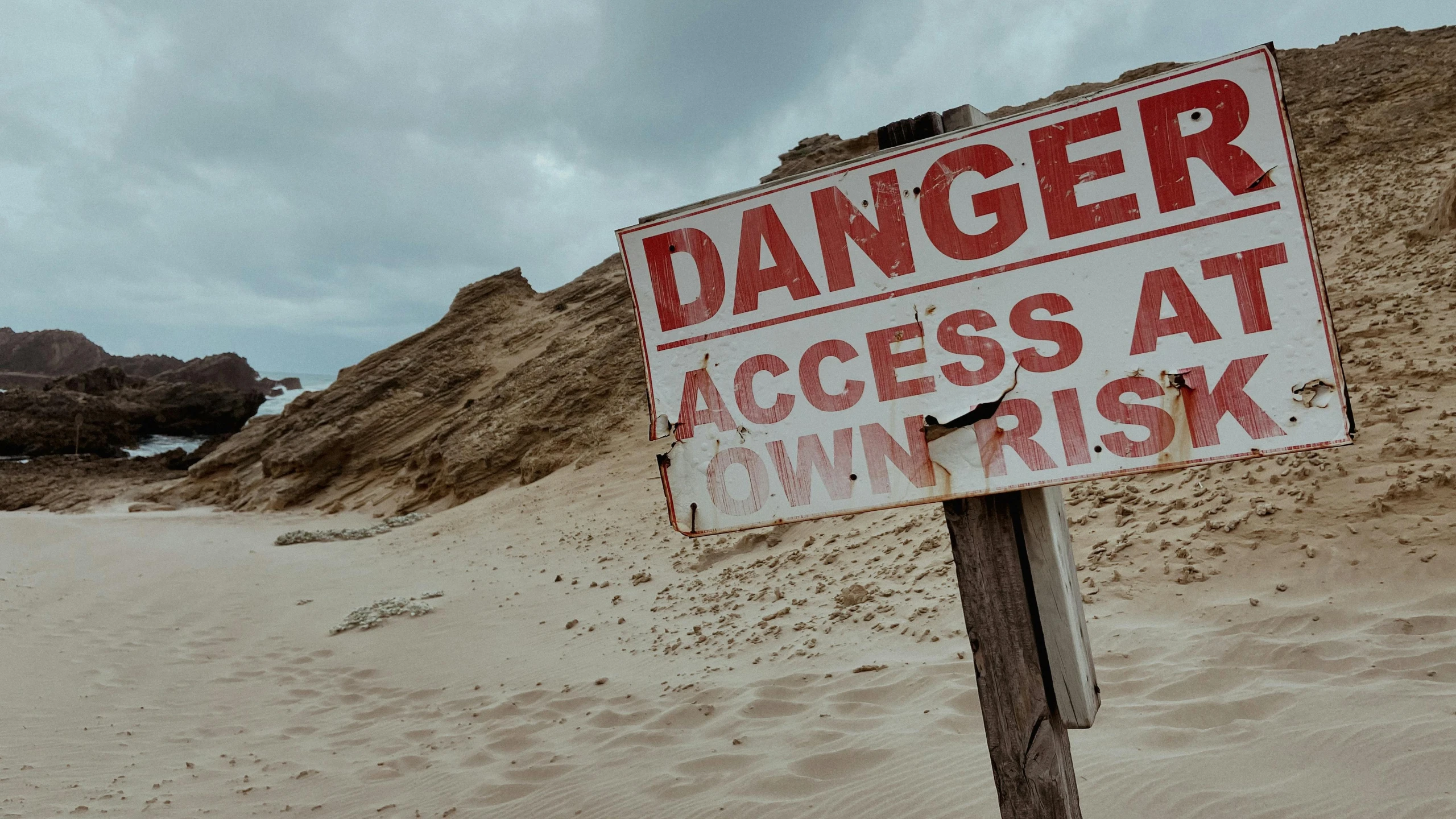 an danger sign is placed on top of a sand dune