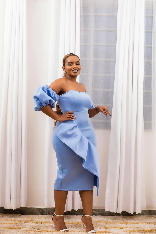 a woman stands in front of white curtains, wearing a light blue dress with a ruffle - front