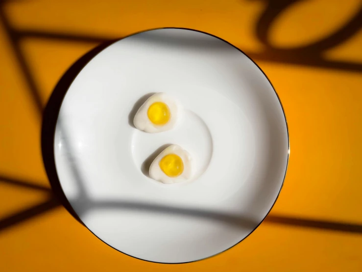 two eggs sit on a white plate against an orange table