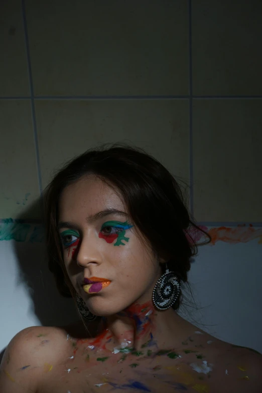 a woman wearing makeup with colorful paint all over her body