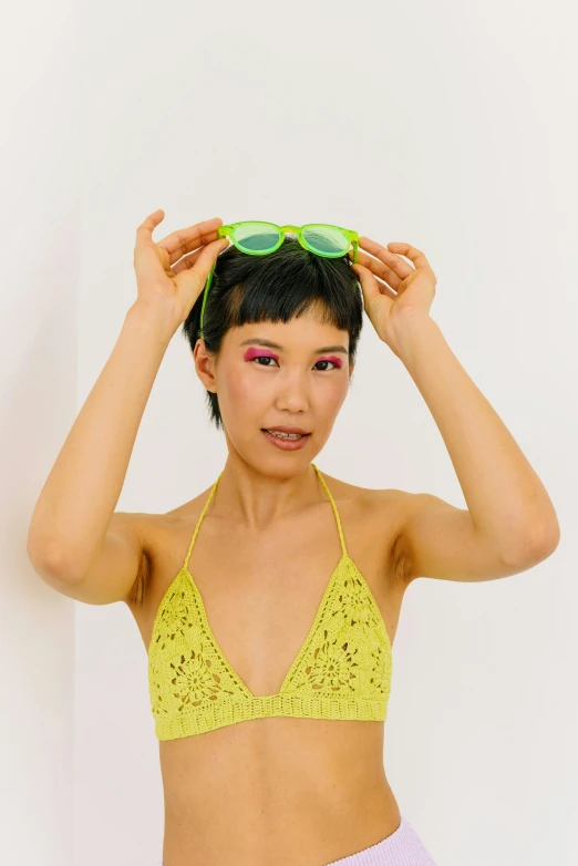 an asian woman in a yellow bikini wears sunglasses