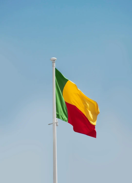 a yellow and red flag on the tip of a white pole