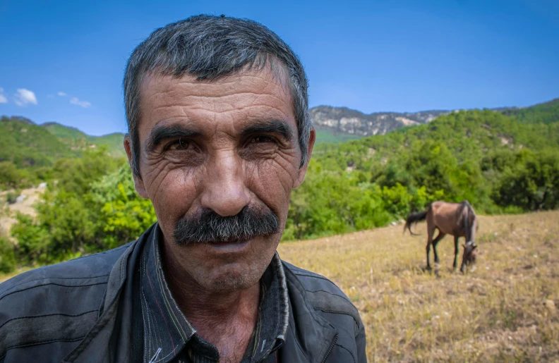 a man with grey hair and a goat in the background