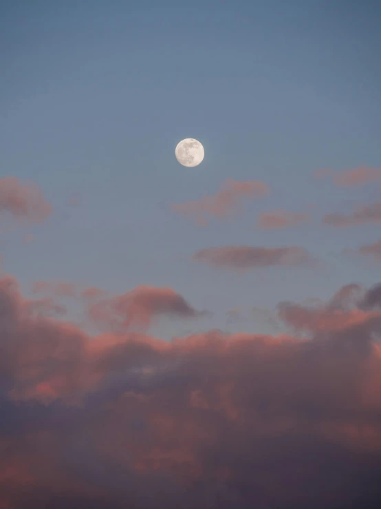 the moon is shining brightly in the blue sky