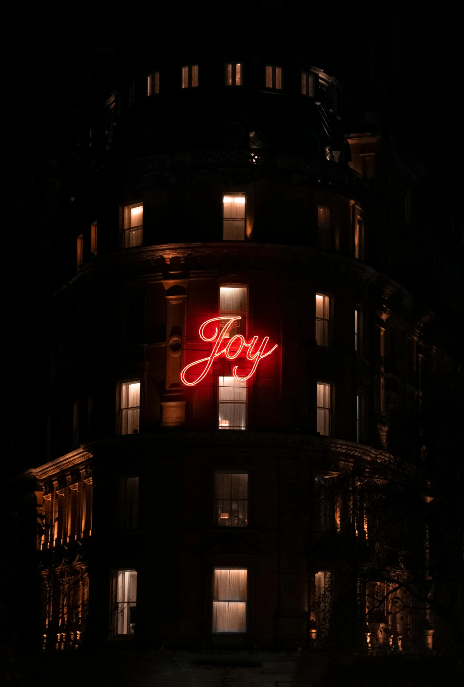 the side of an apartment building is lit up at night with a sign that says lazy