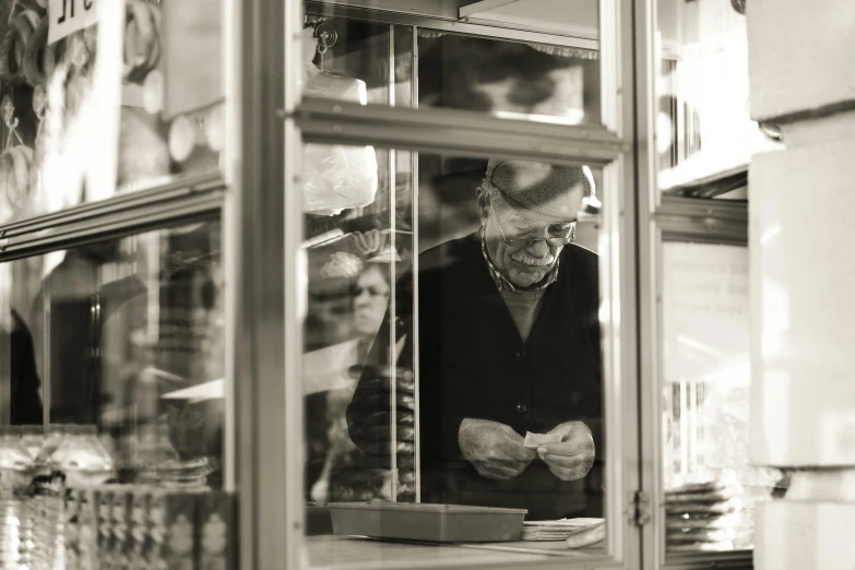 an old man sitting outside of a bakery