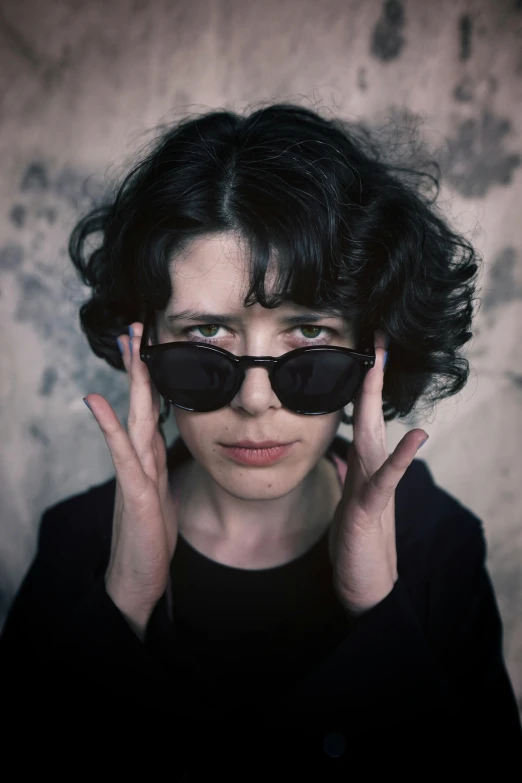 a woman in glasses is holding her hair in one hand