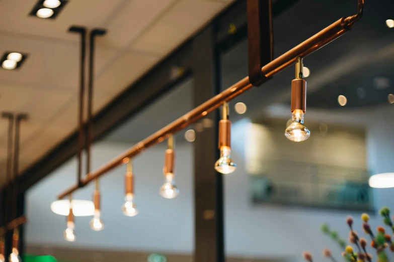 several light bulbs hanging from a rail in front of windows