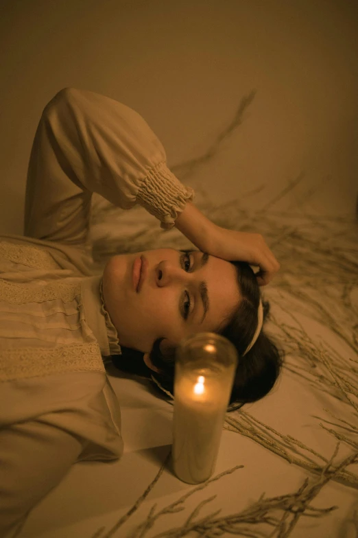 a woman laying on a bed next to a lit candle