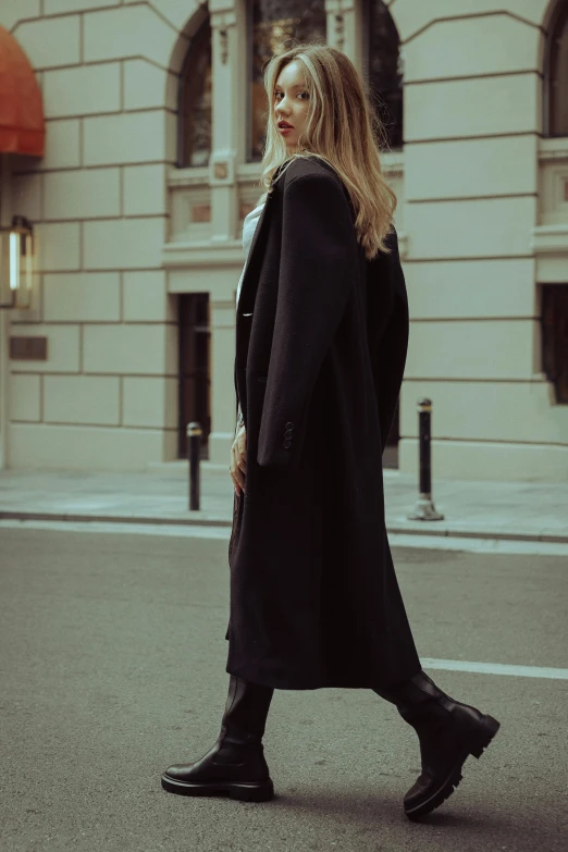 a woman walking down the street in an overcoat